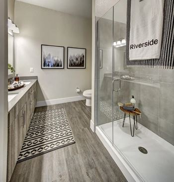 A bathroom with a glass shower stall and a towel hanging on the glass door.
